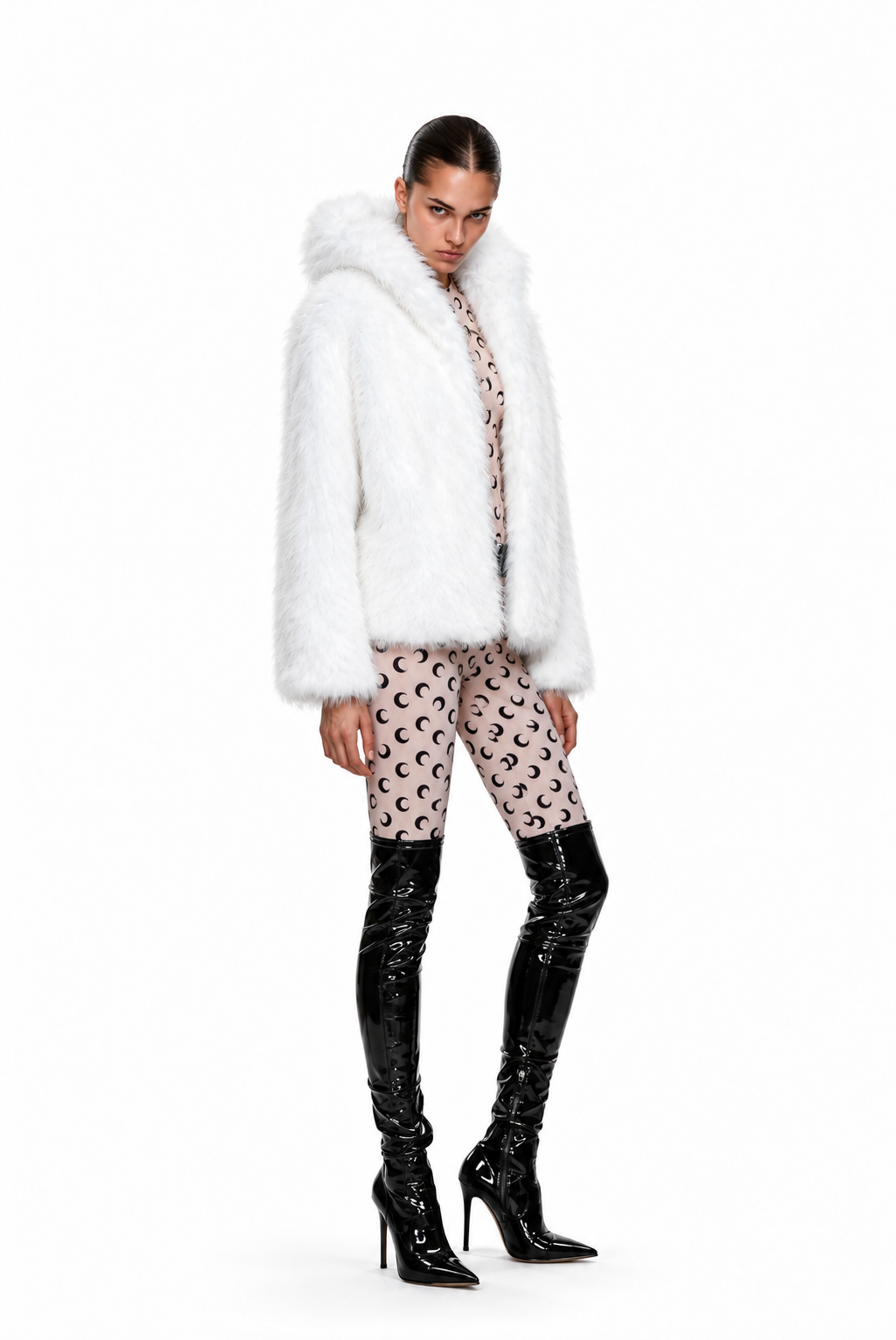 A model wearing a white faux fur jacket with a large plush collar, paired with pink patterned leggings and shiny black patent leather knee-high boots, shot against a solid white background.