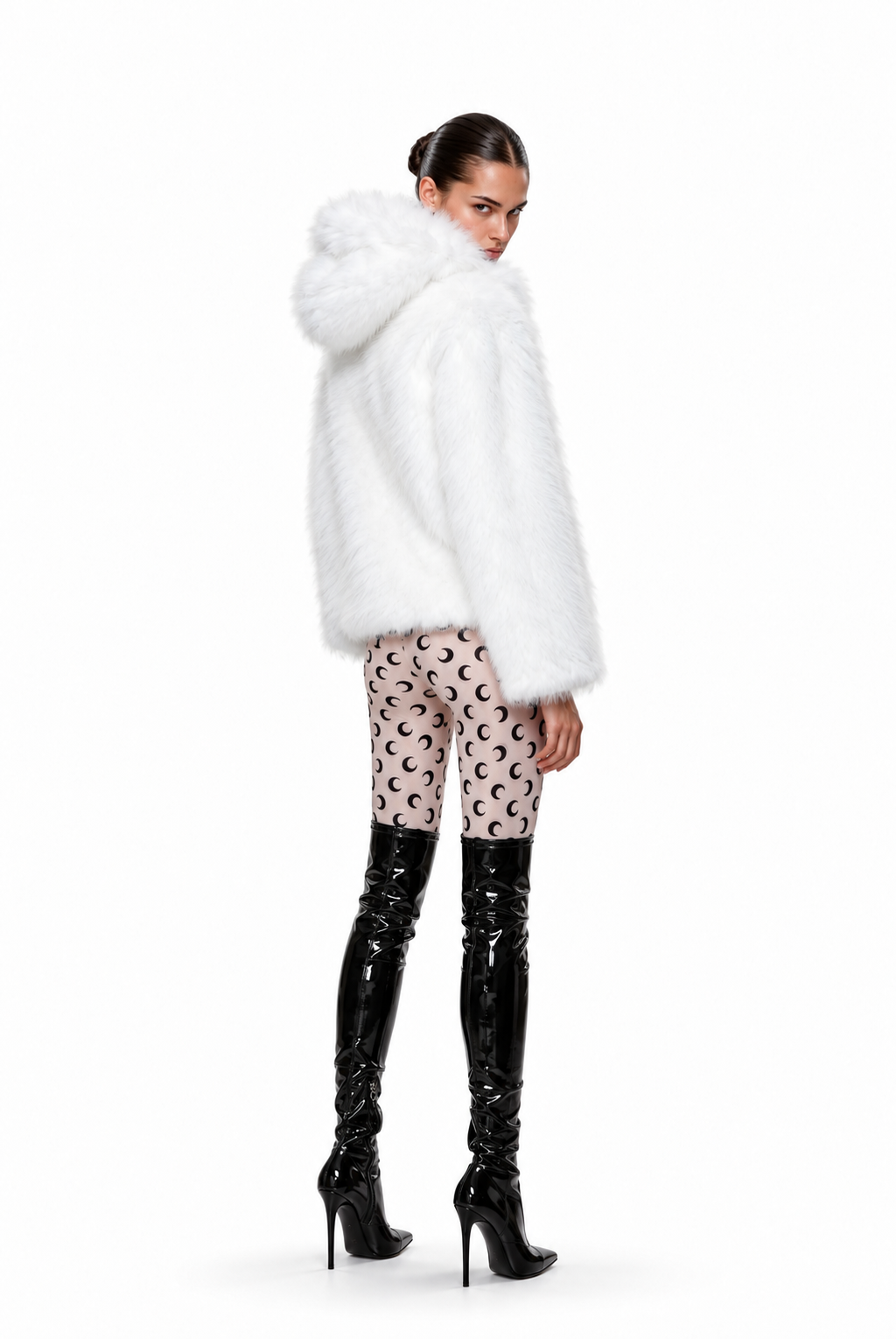 A model is shown from the back wearing a voluminous white faux fur hooded jacket, patterned pink and beige leggings, and black patent leather over-the-knee boots against a plain white background.