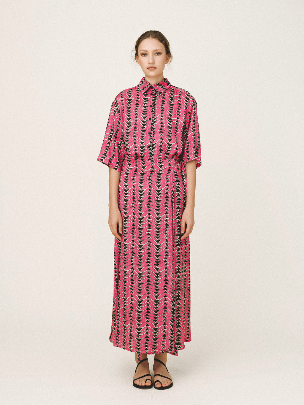 Woman wearing a pink and black patterned dress on a white background