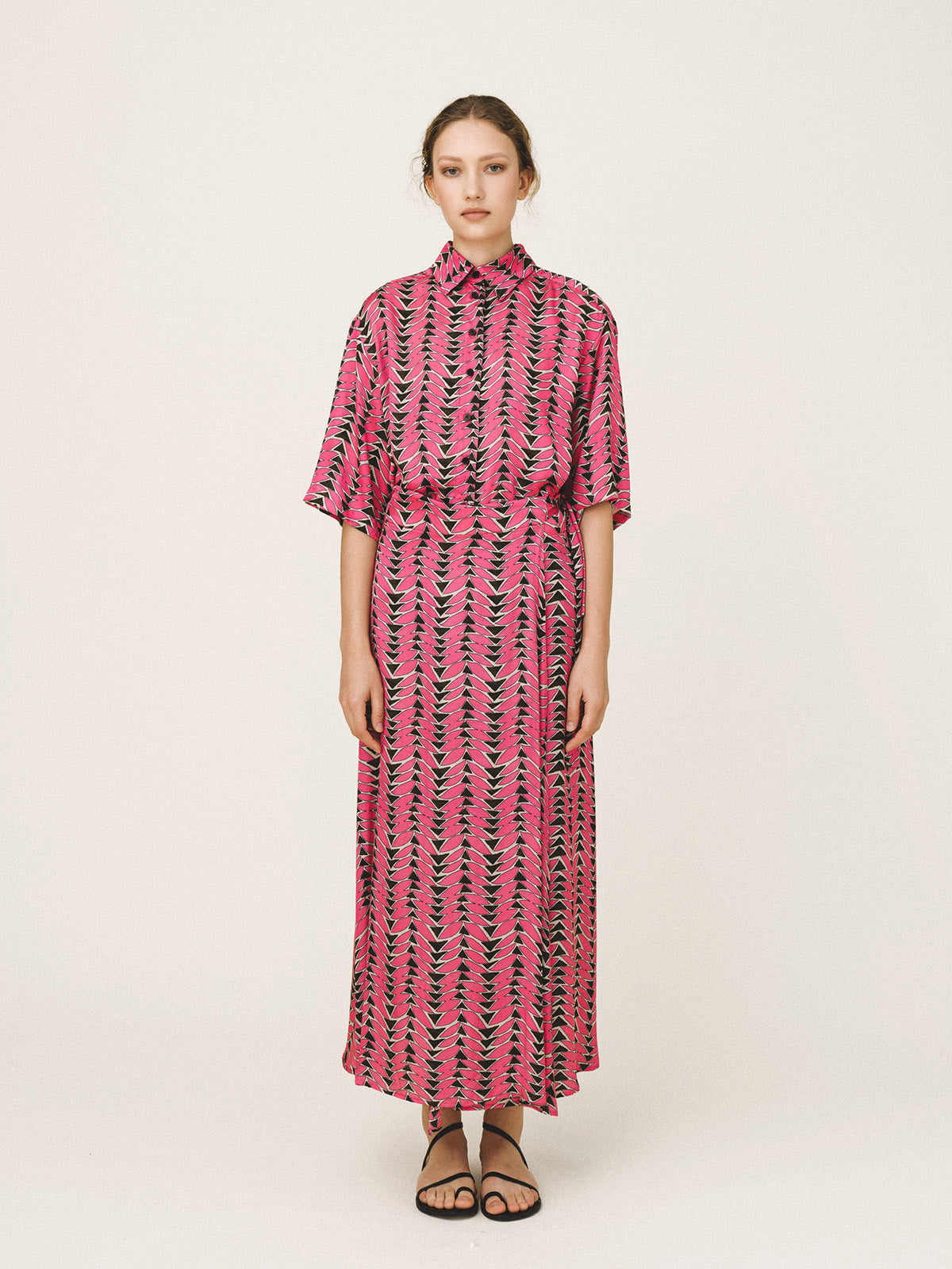 Woman wearing a pink and black patterned dress on a white background