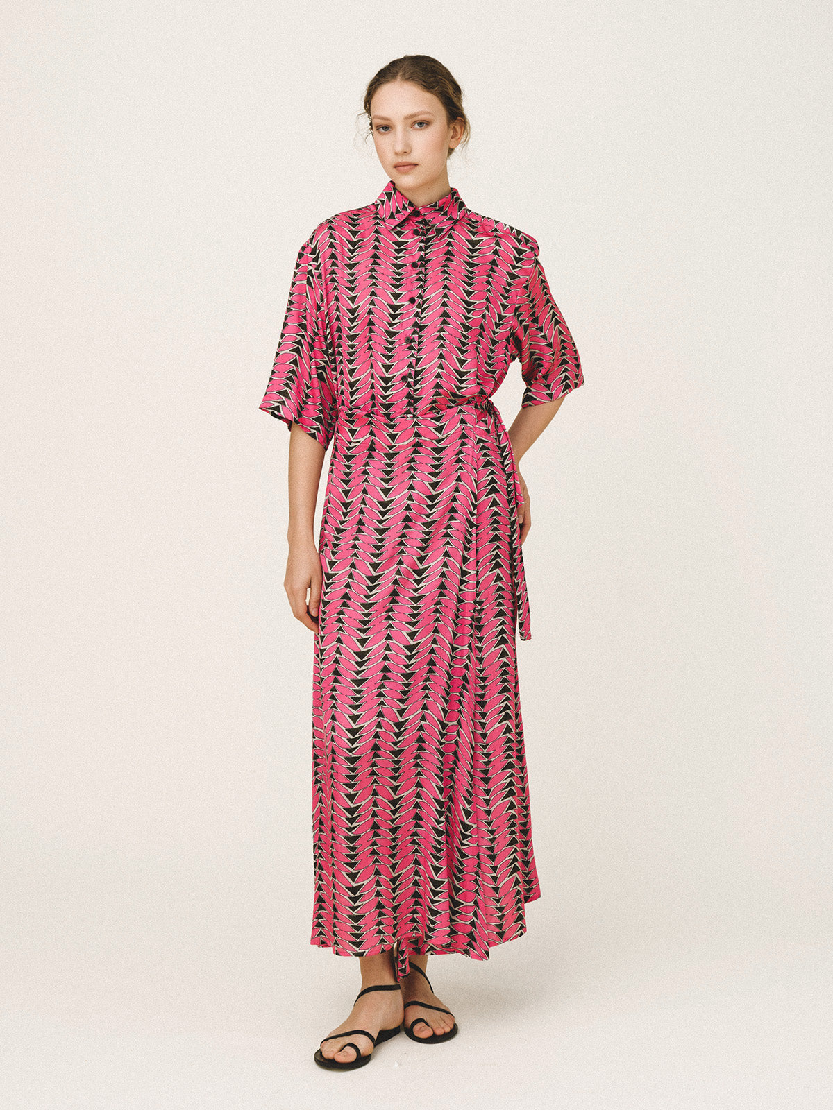Woman wearing a pink and black patterned dress on a white background