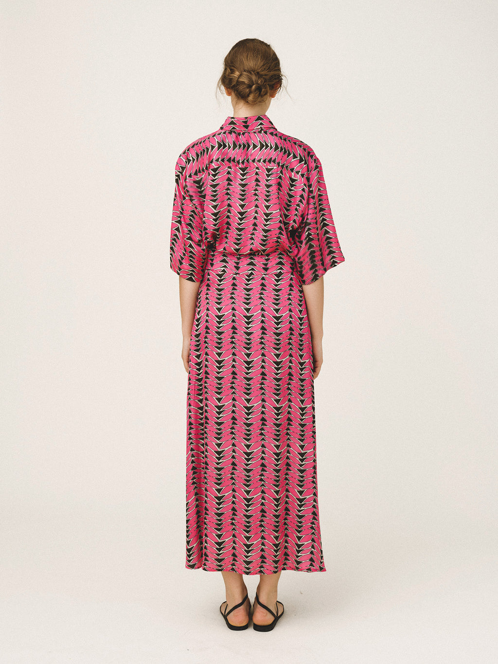 Woman wearing a pink and black patterned dress on a white background