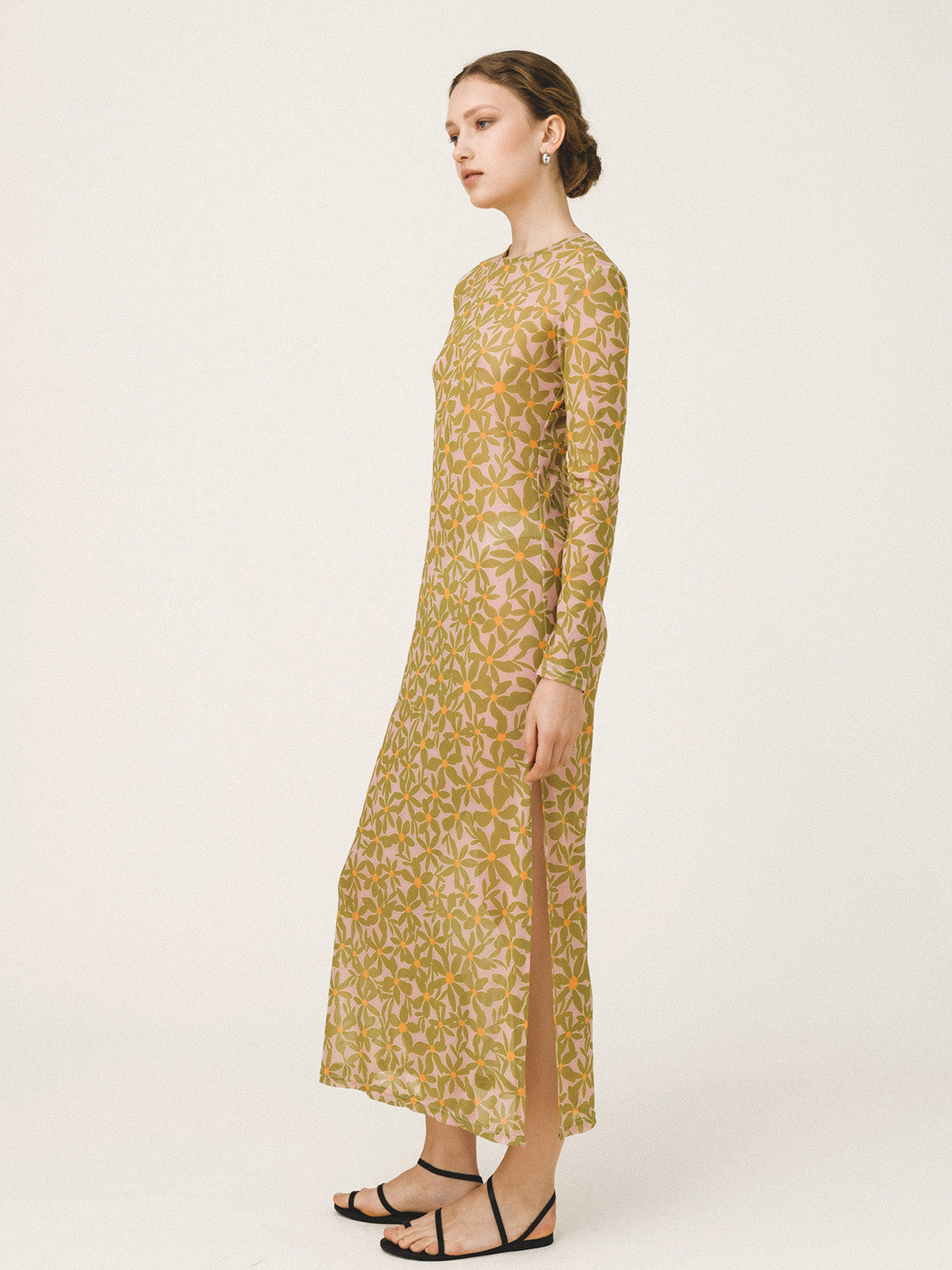 Woman wearing a long-sleeve, patterned dress on a white background