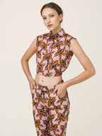Woman wearing a sleeveless top and pants with a leaf pattern on a plain background