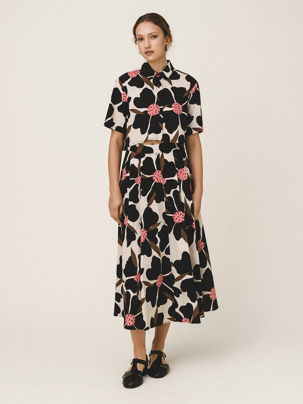 Woman wearing a floral dress with black, pink, and beige pattern on a white background