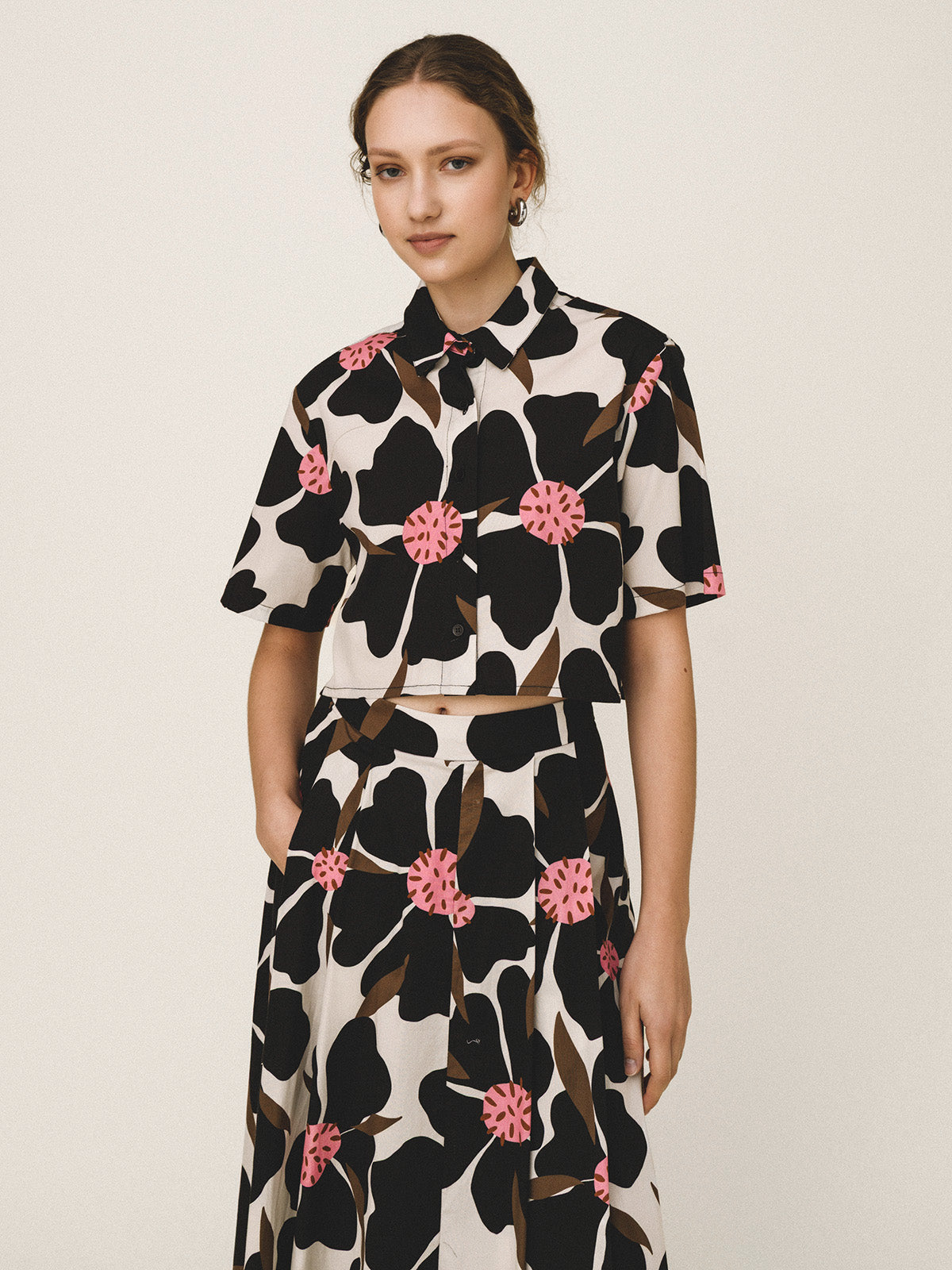 Woman wearing a black and white floral dress with pink flowers on a beige background