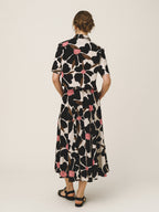 Woman wearing a floral dress with a black and white pattern on a plain background
