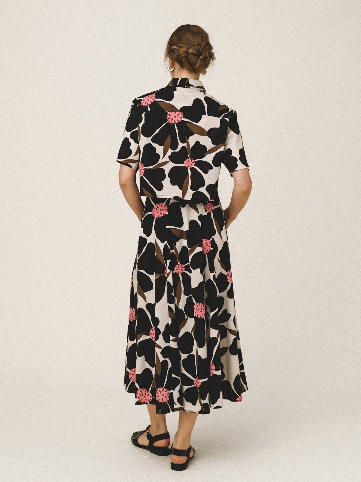 Woman wearing a floral dress with a black and white pattern on a plain background