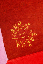 Red towel with yellow sun design and text on a red background