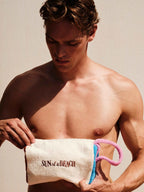 Man holding a towel with 'Sun of a Beach' text against a neutral background