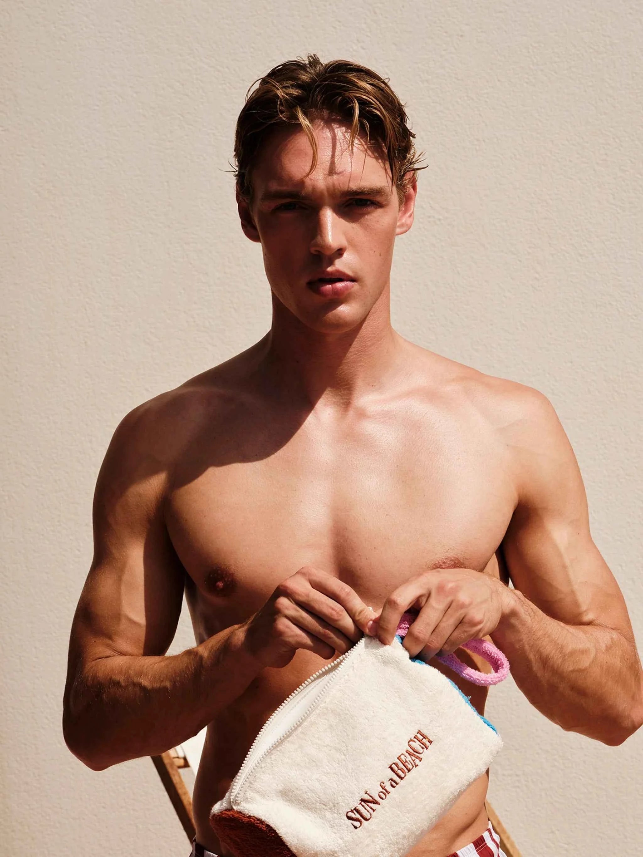 Man holding a towel with 'Saint Laurent' branding against a beige background