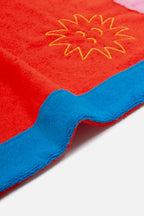 Red towel with yellow sun design and blue border on a white background