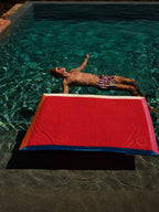 Person lying on a red and blue mat above a pool