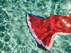 Red fabric with blue trim floating on clear water