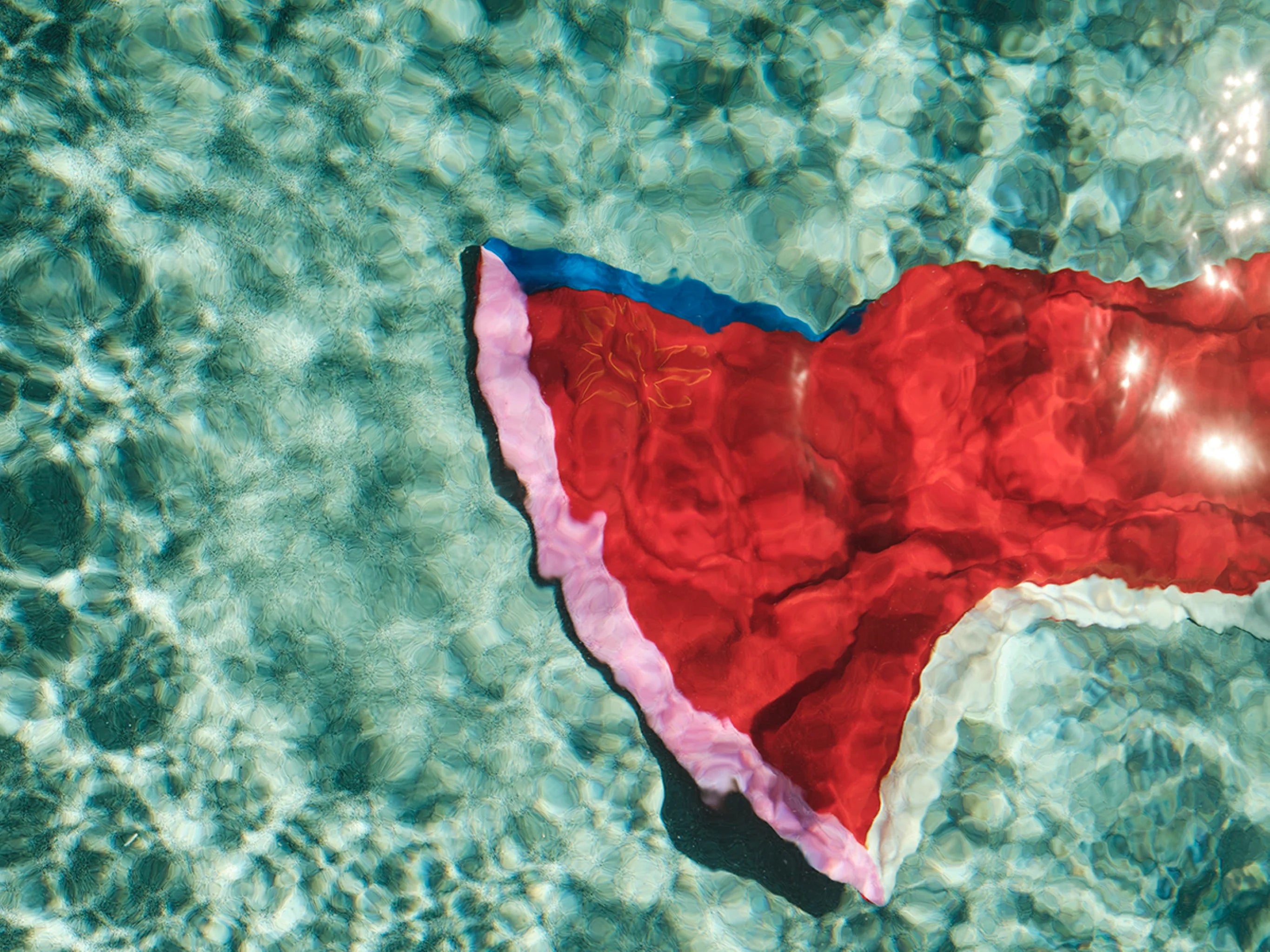 Red fabric with blue trim floating on clear water
