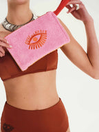Person wearing a brown bikini holding a pink towel with 'Sun & Beach' logo.