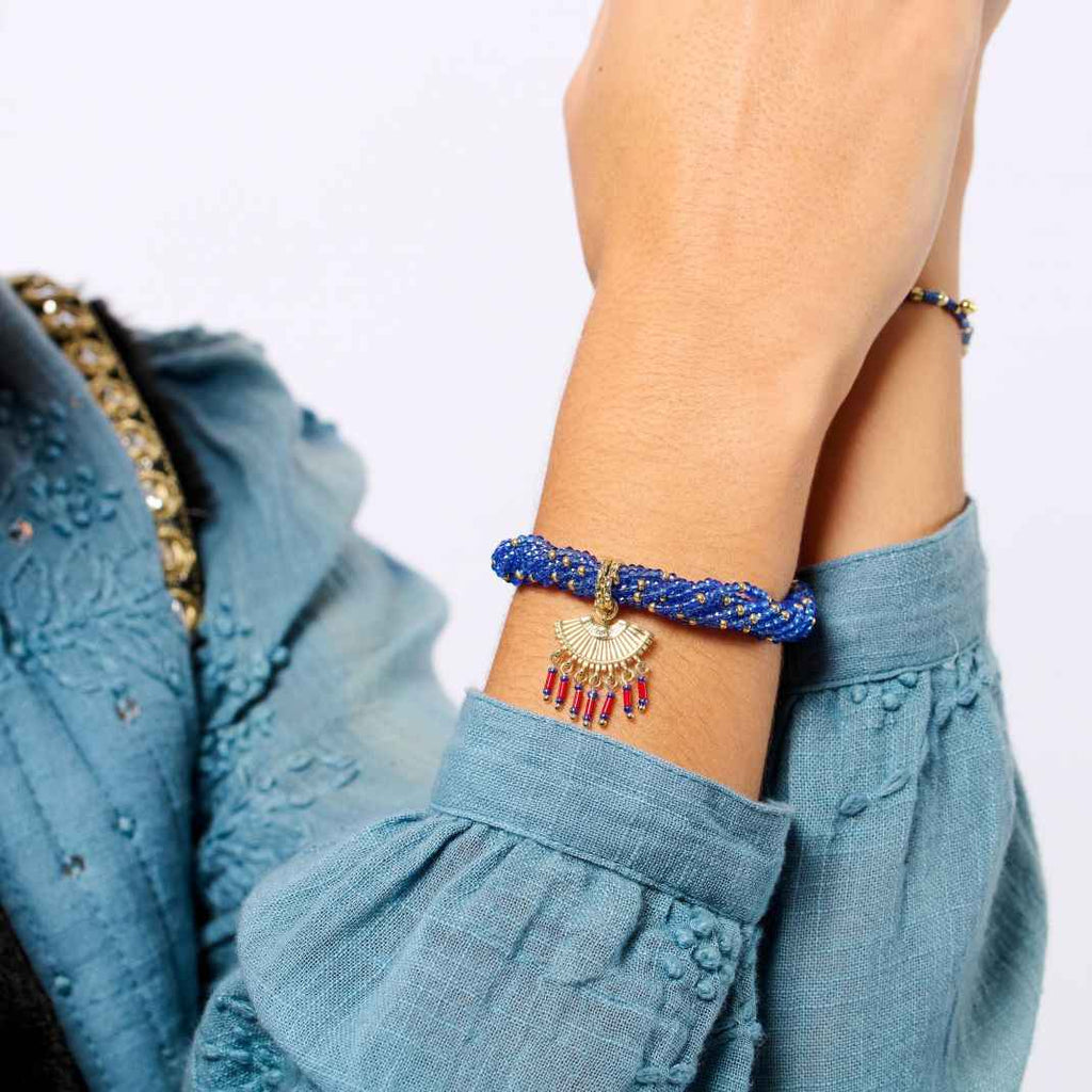 Person wearing a blue beaded bracelet with a plain background
