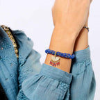 Person wearing a blue beaded bracelet with a plain background