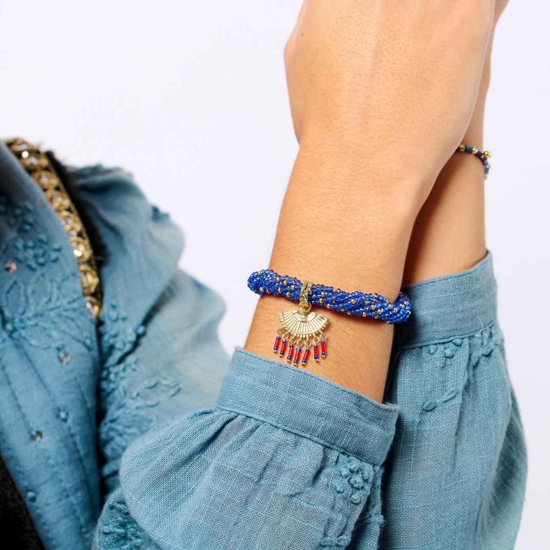Person wearing a blue beaded bracelet with a plain background