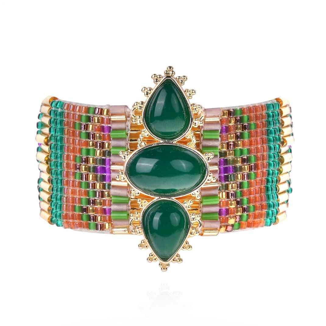 Multicolored beaded clutch with green gemstones on a white background