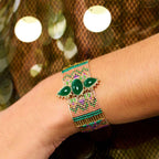 Bracelet with green stones on a wrist against a blurred background