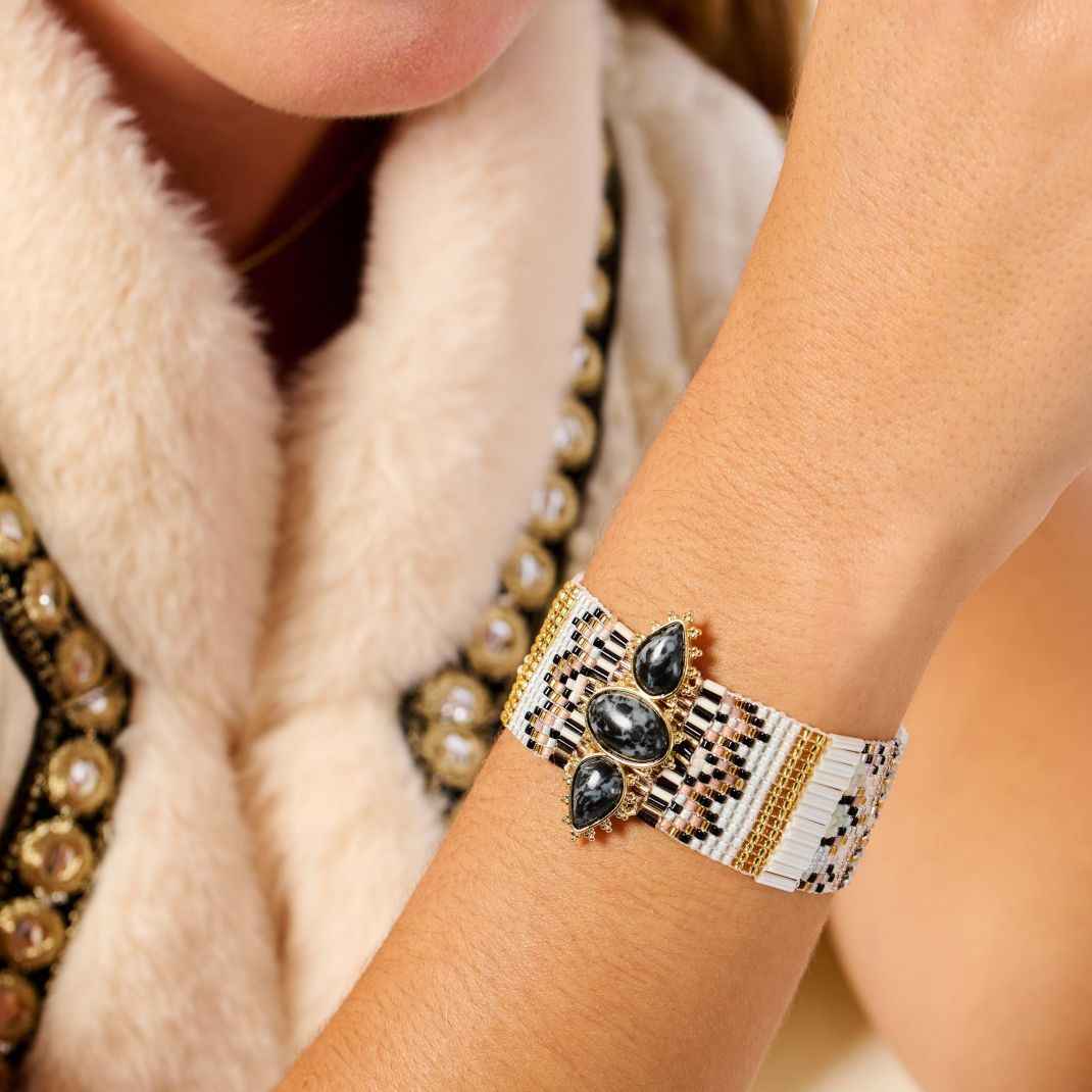 Close-up of a person's wrist wearing a decorative bracelet with black stones and gold accents.