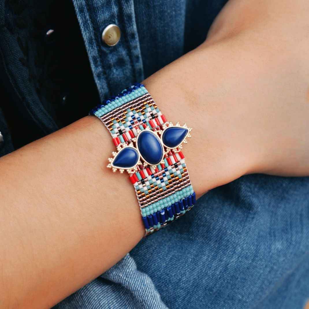 Beaded bracelet with blue stones on a wrist, against a denim background