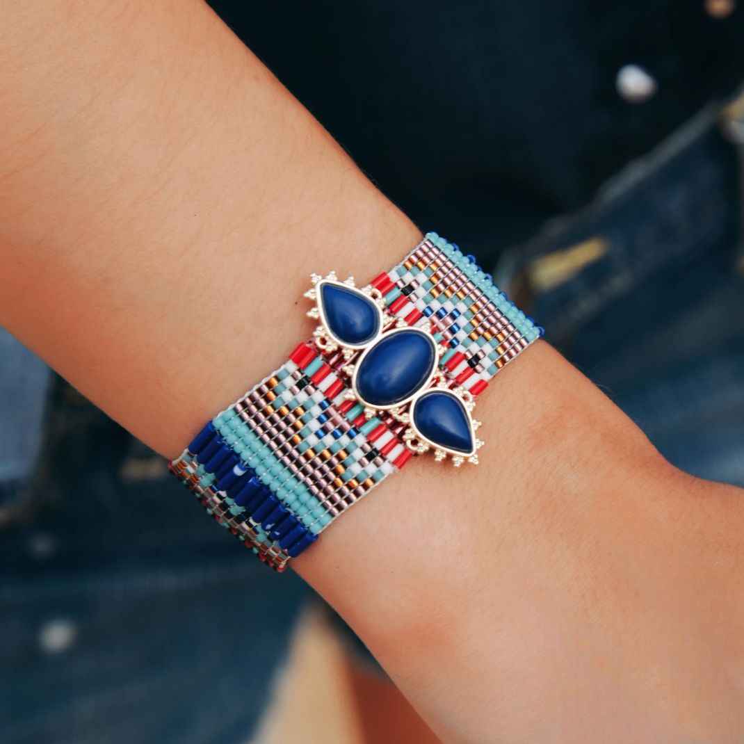 Colorful beaded bracelet with blue stones on a wrist against a blurred denim background