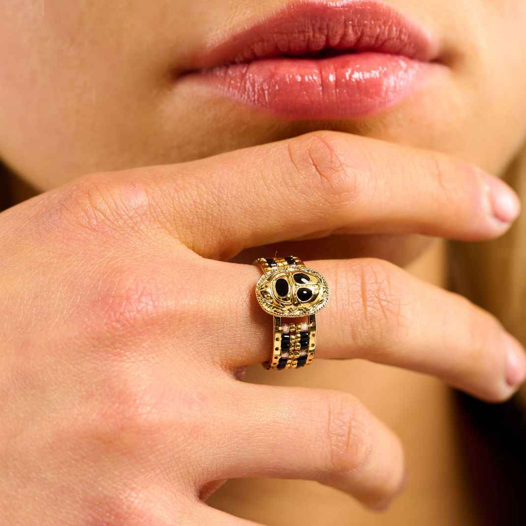 Close-up of a hand wearing a gold ring with a black gemstone.