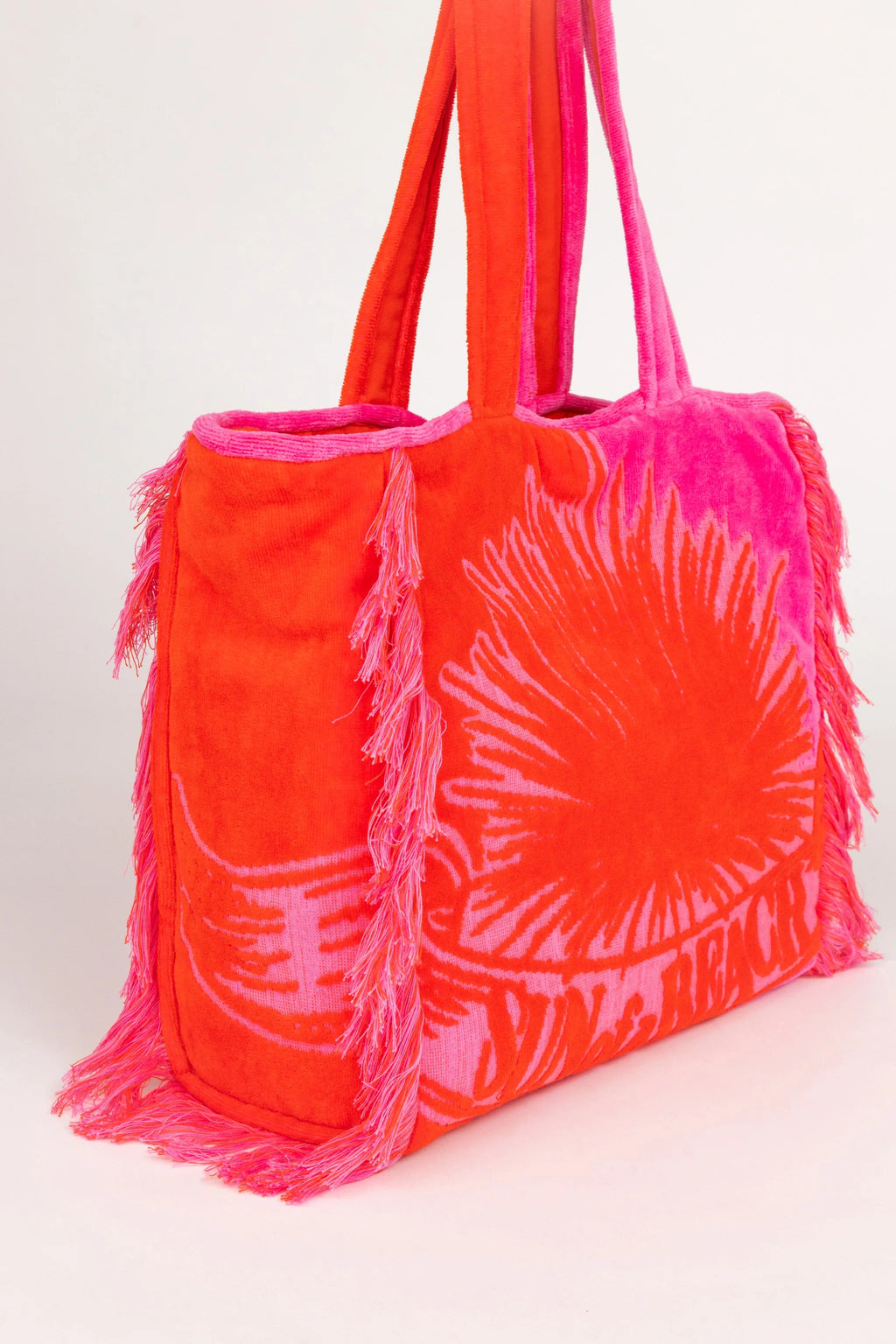 Orange tote bag with pink fringe and leaf pattern on a white background
