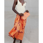 Person wearing an orange patterned skirt with a plain background