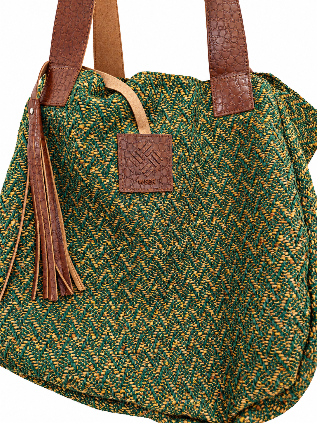 A green and yellow woven tote bag with brown textured leather handles and a matching leather brand patch on the front.