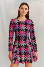 Woman wearing a colorful houndstooth pattern dress on a plain background