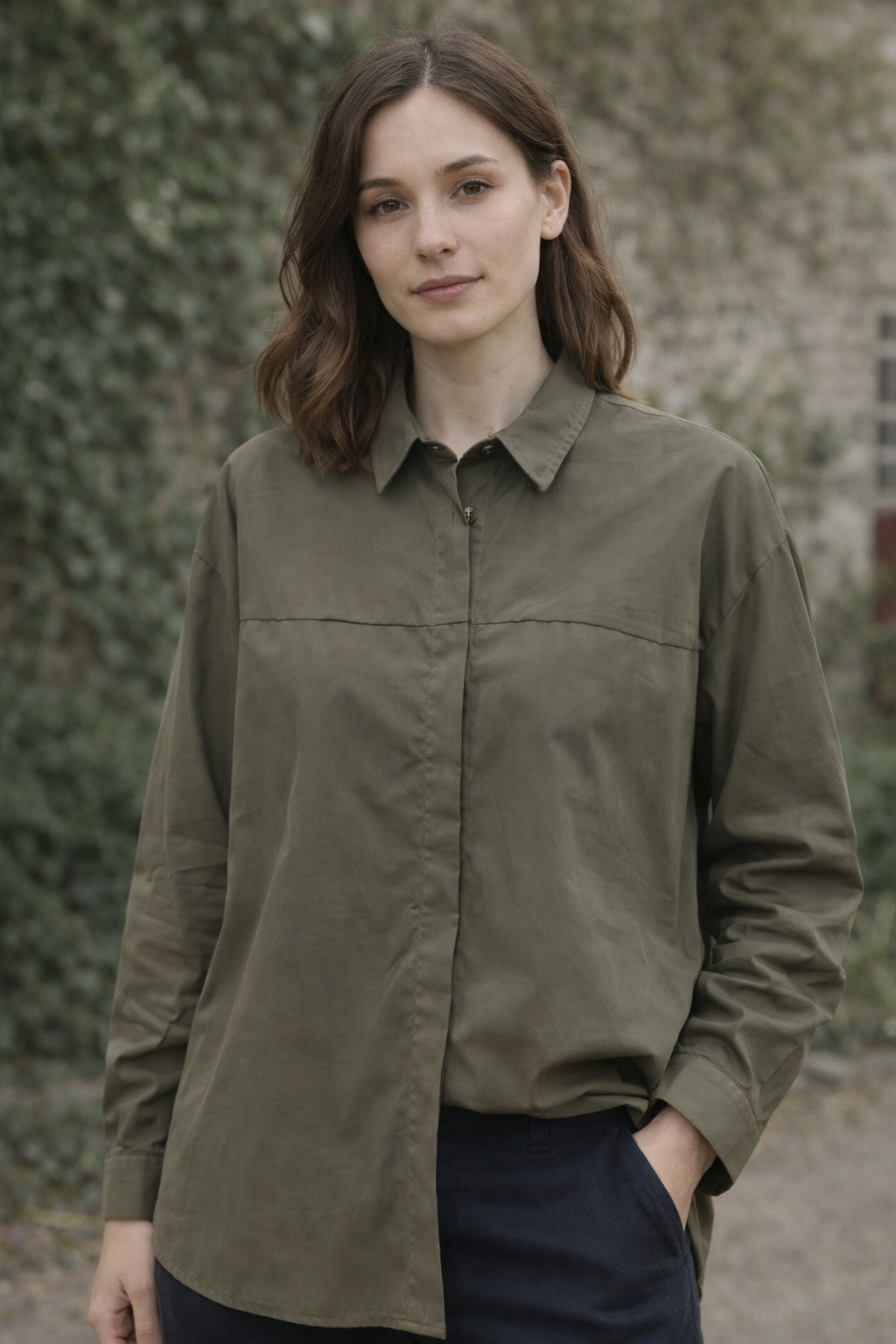 Woman wearing an olive green shirt outdoors with a blurred natural background