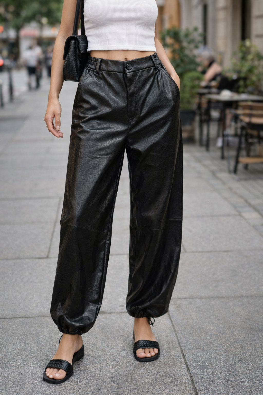 Person wearing black shiny pants on a city street