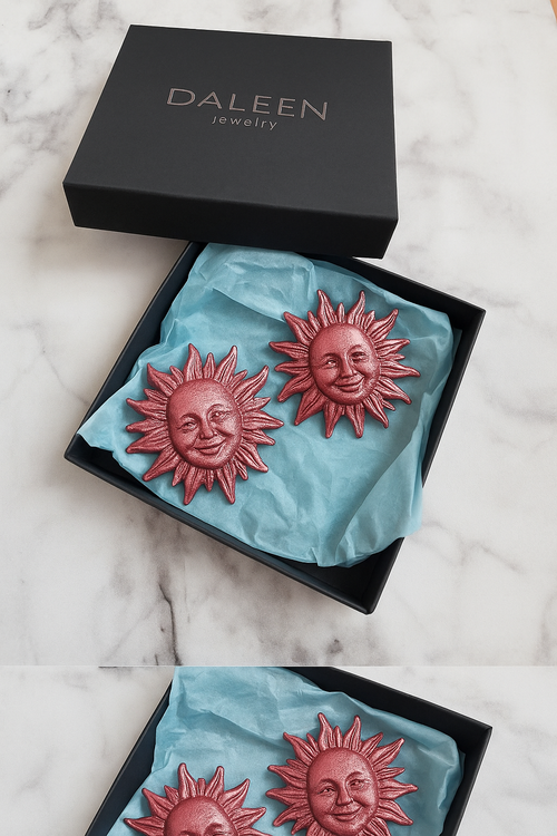 Sun-shaped earrings in a black Daleen jewelry box on a marble surface