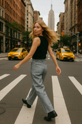 Woman crossing a city street with yellow taxis and tall buildings in the background