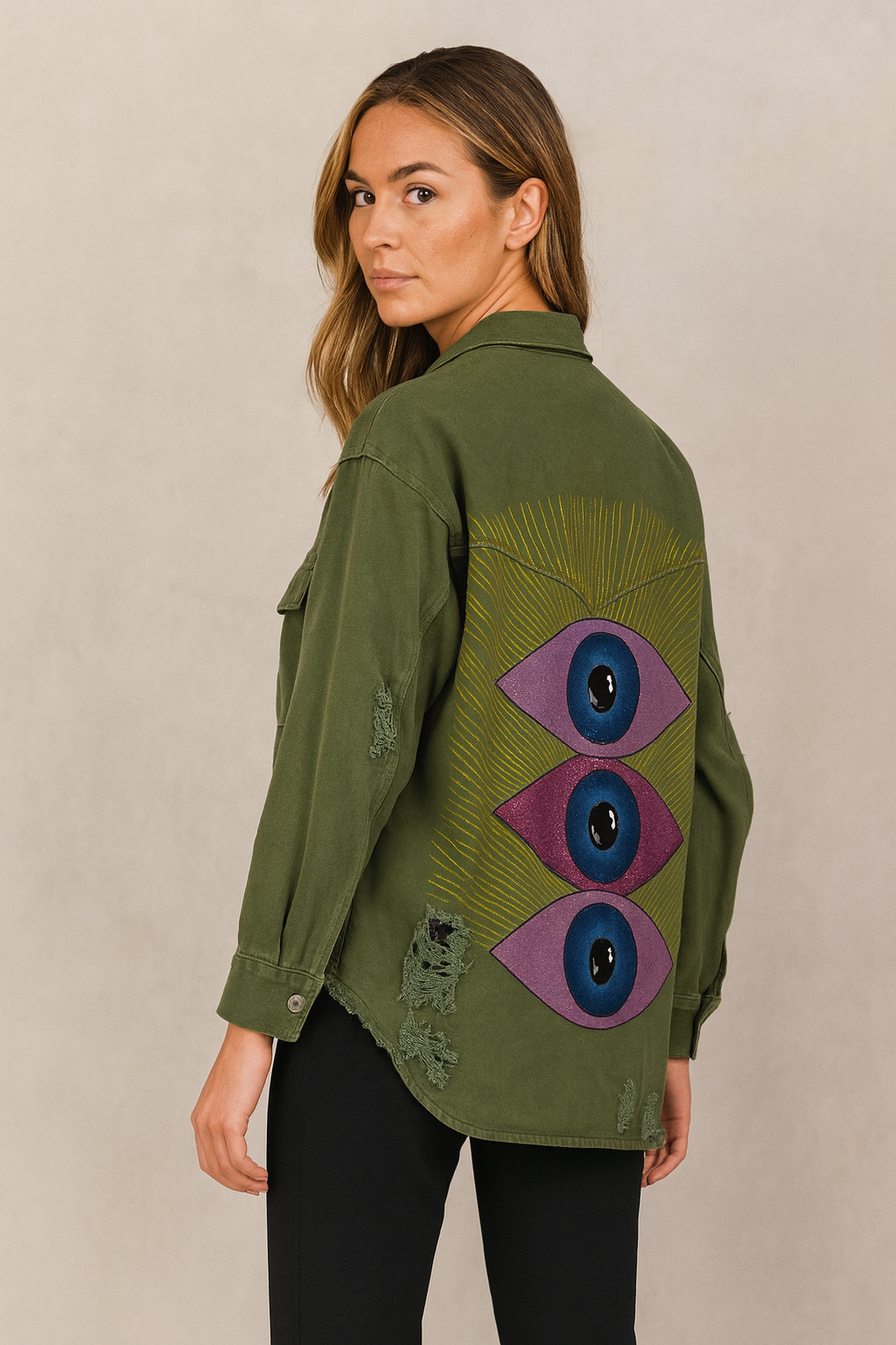 Woman wearing a green jacket with eye designs on a beige background