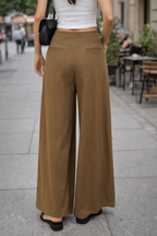 Person wearing brown wide-leg pants on a city street.