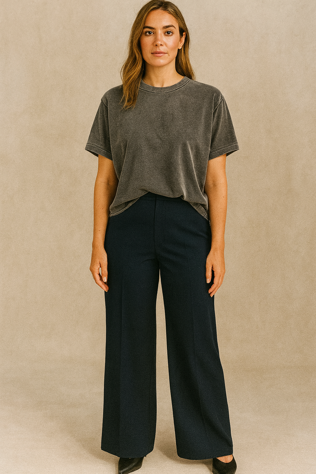 Woman wearing a gray t-shirt and black pants against a beige background