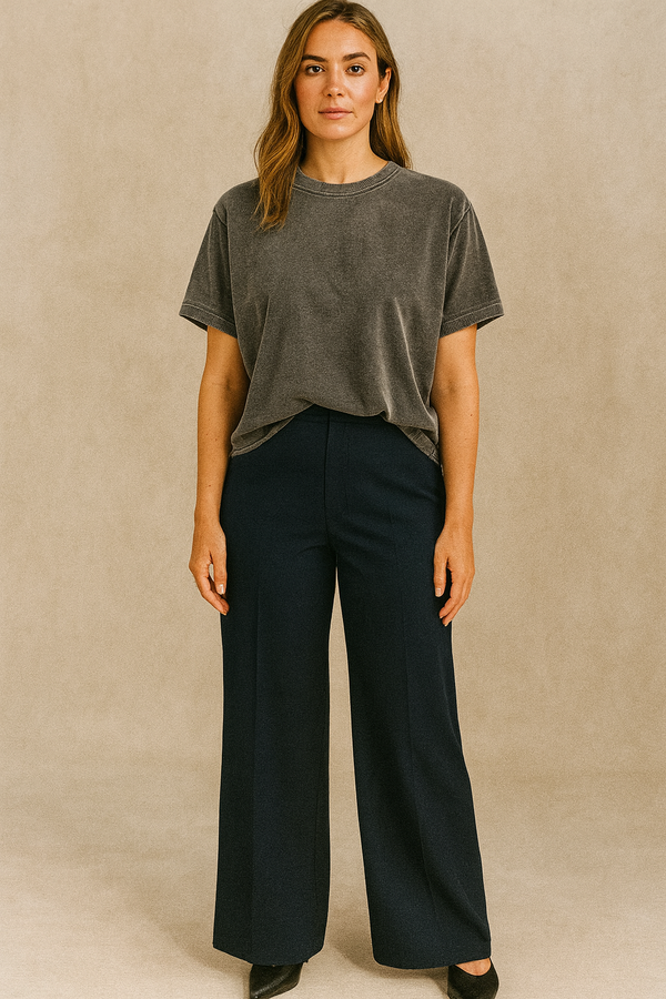 Woman wearing a gray t-shirt and black pants against a beige background