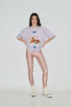 Person wearing a graphic t-shirt and patterned leggings on a white background