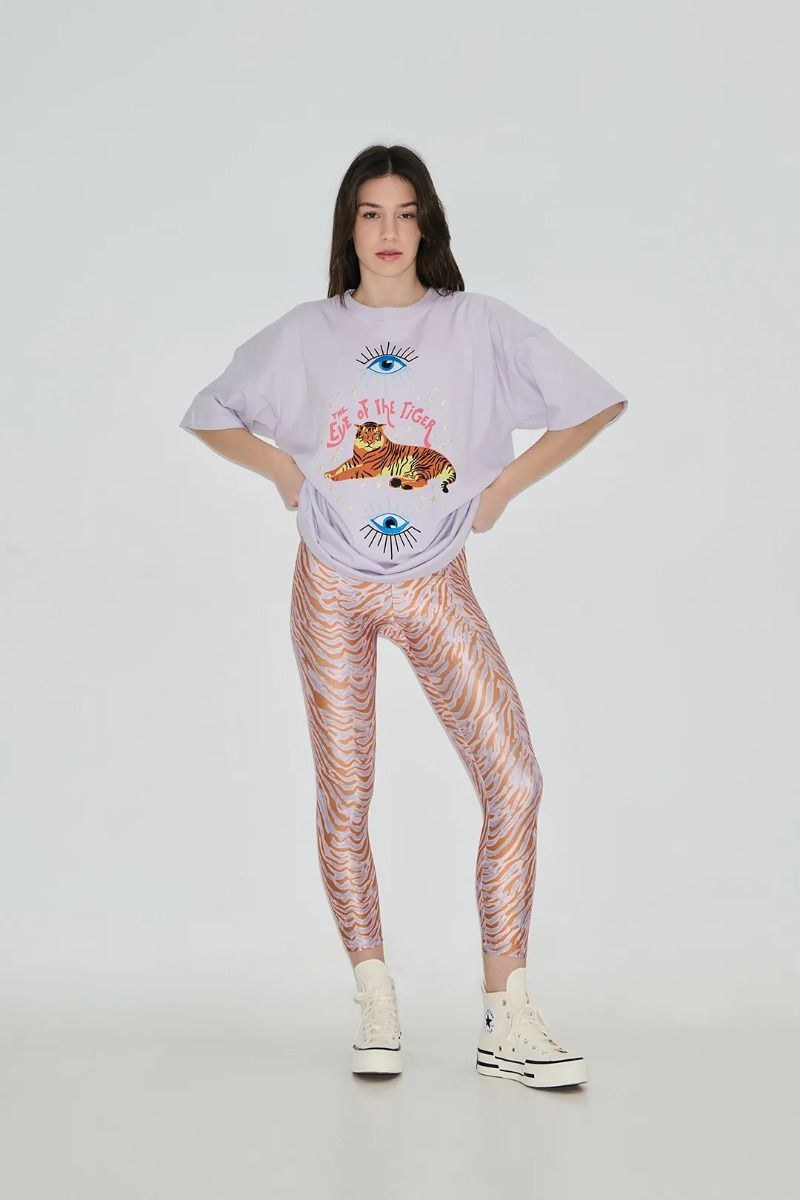 Person wearing a graphic t-shirt and patterned leggings on a white background
