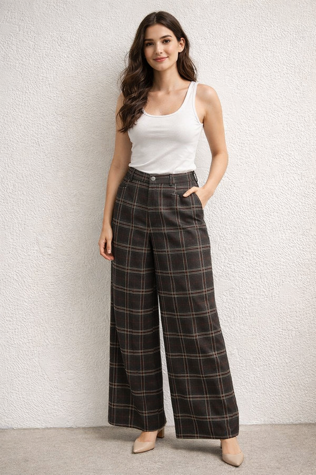 Woman wearing a white tank top and plaid pants against a light background