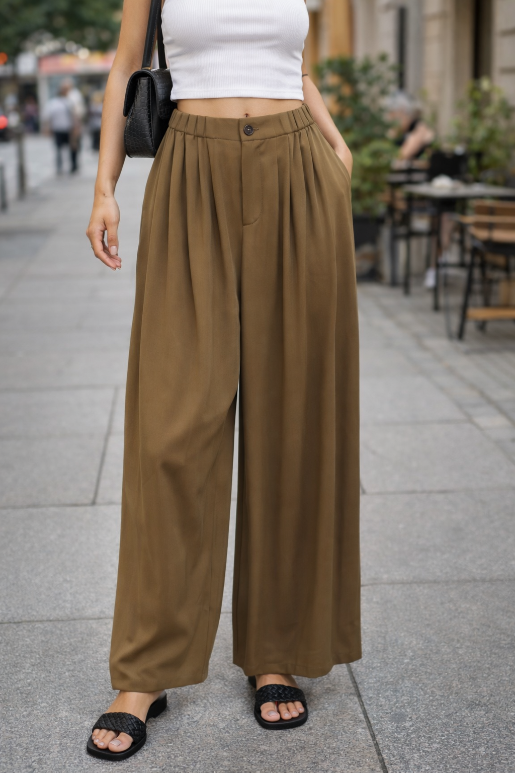 Person wearing brown wide-leg pants on a city street.