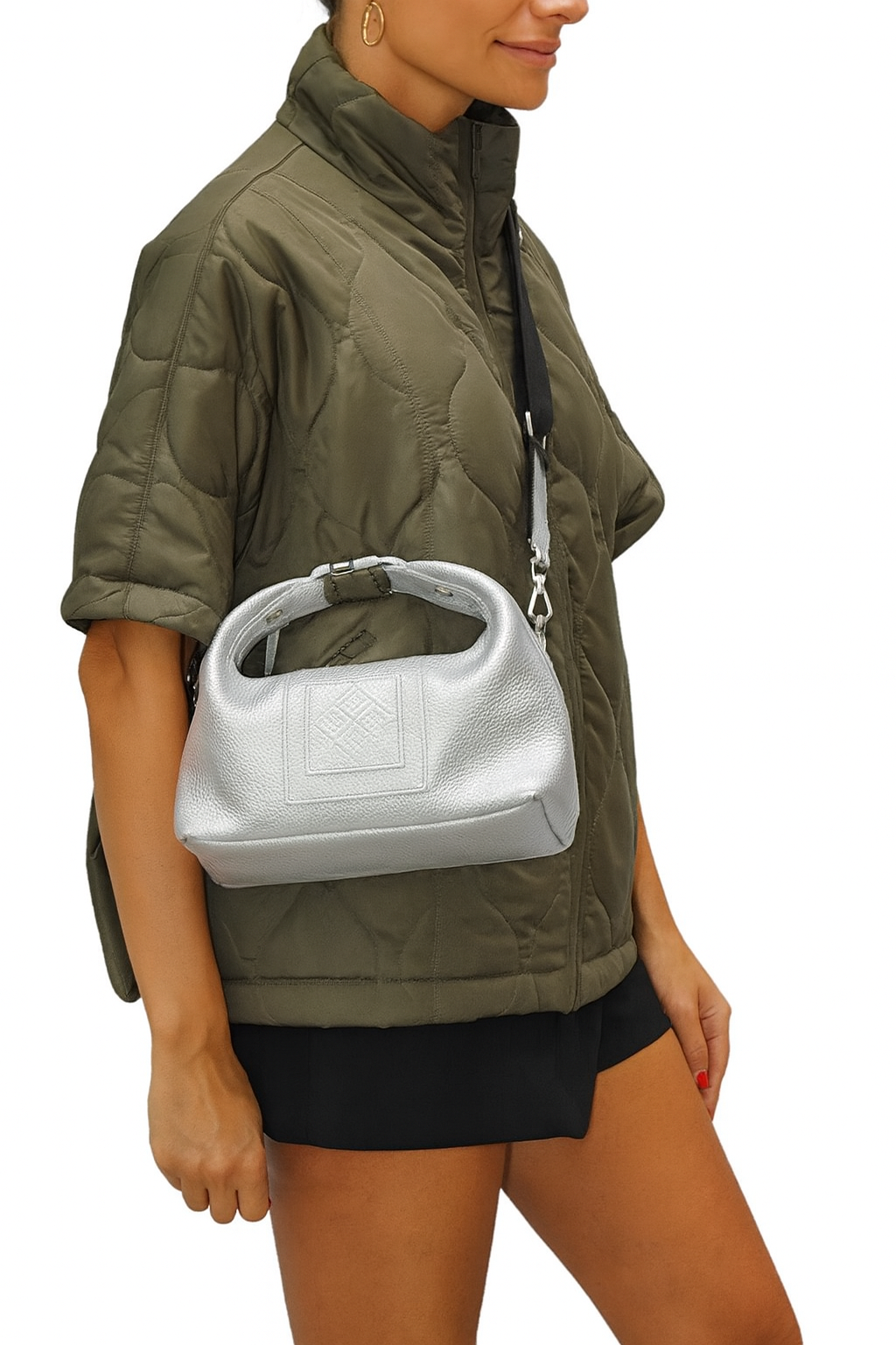 Person wearing a green jacket and black skirt holding a white handbag on a white background