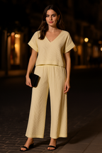 Woman in a light yellow outfit standing outdoors at night.