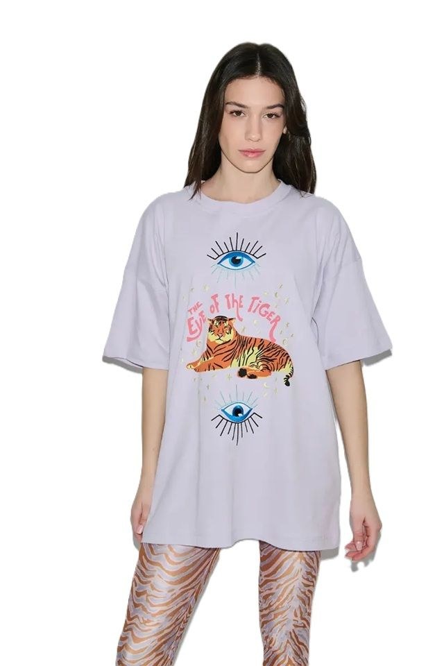 Woman wearing a light gray oversized t-shirt with tiger and eye designs on a white background