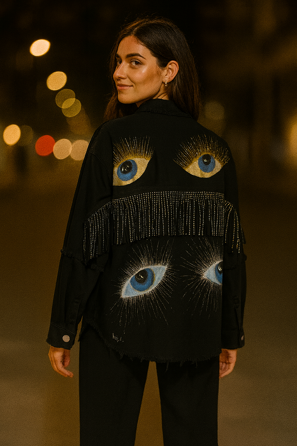 Woman wearing a black jacket with eye designs against a blurred lights background