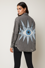 Person wearing a gray "Eye" See You jacket with a blue eye design on the back against a plain background